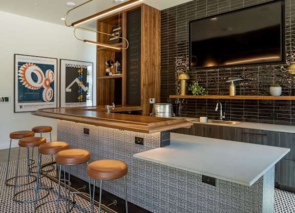 A modern kitchen with a bar area and a television above it.