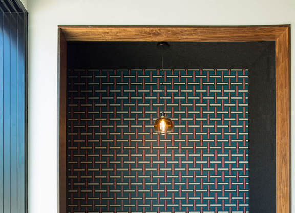 A black and white tiled wall with a wooden frame and a table and bench in front of it.