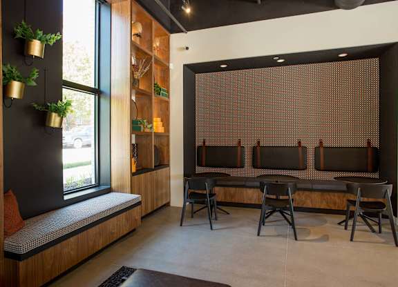A room with a bench, chairs and a window.