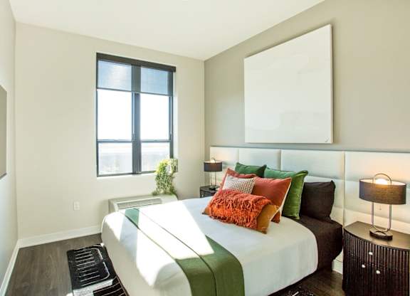 A bedroom with a bed, pillows, and a lamp.