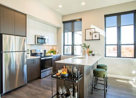 A modern kitchen with a stainless steel refrigerator and a bar area.