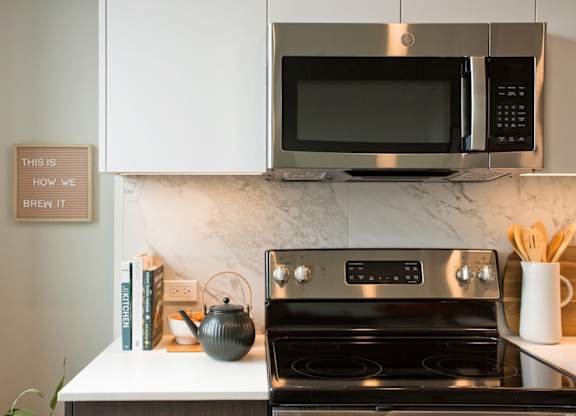 A modern kitchen with a stove, microwave, and a sign that says