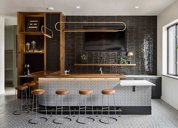A modern kitchen with a bar area and stools.