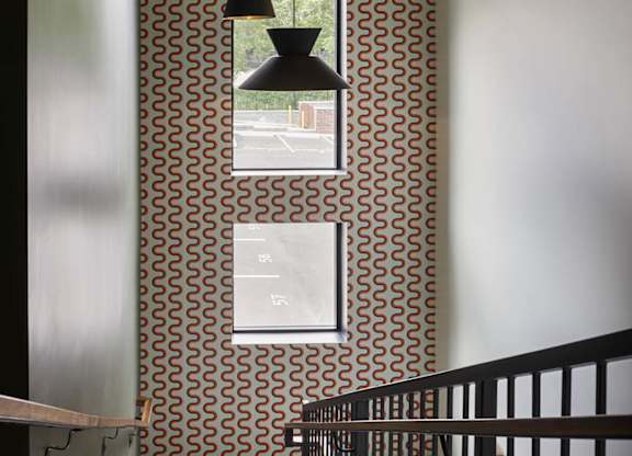 A hallway with a black railing and a wallpapered wall with a pattern of circles.
