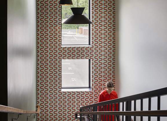 A man in a red shirt is walking down a staircase.