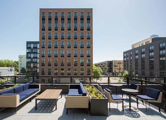 A brown building with a balcony that has a table and chairs.