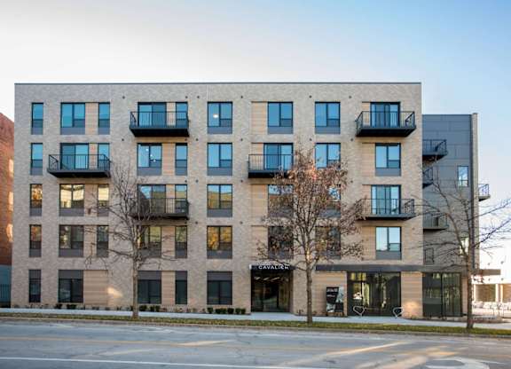 A modern apartment building with balconies and a storefront on the ground floor.