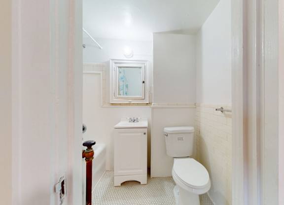 A white toilet sits next to a white sink in a small bathroom.