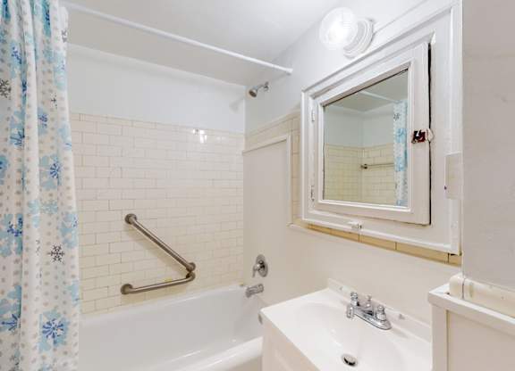 A white bathroom with a tub, sink, and mirror.