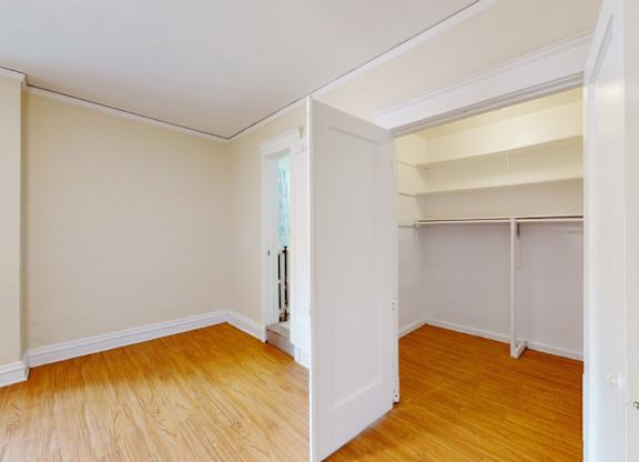 A room with a white door and wooden flooring.
