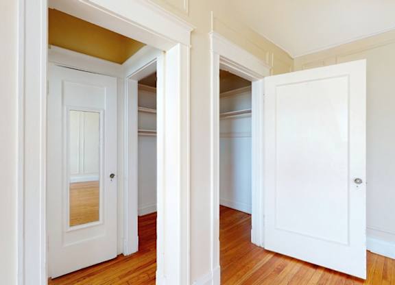 A white door is open to a room with wooden floors.