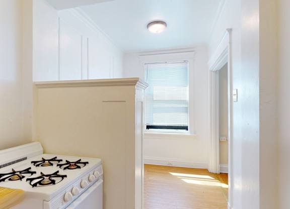 A white gas stove in a kitchen with a window.