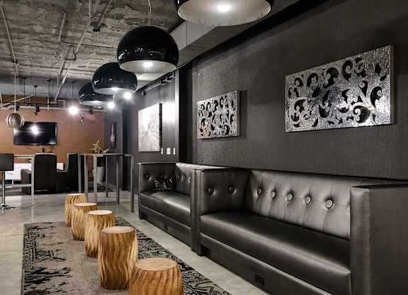 A modern living room with a dark grey sofa and wooden stumps on the floor.