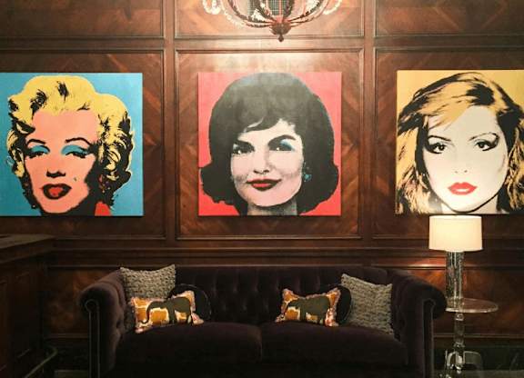 Three portraits of women are displayed on a wall above a couch.