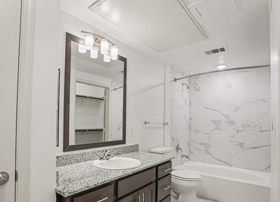 A bathroom with a marble patterned wall and a white toilet.