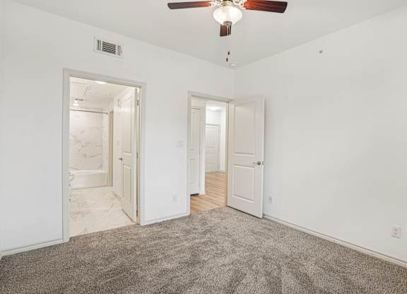 A room with a ceiling fan and carpeted floor.