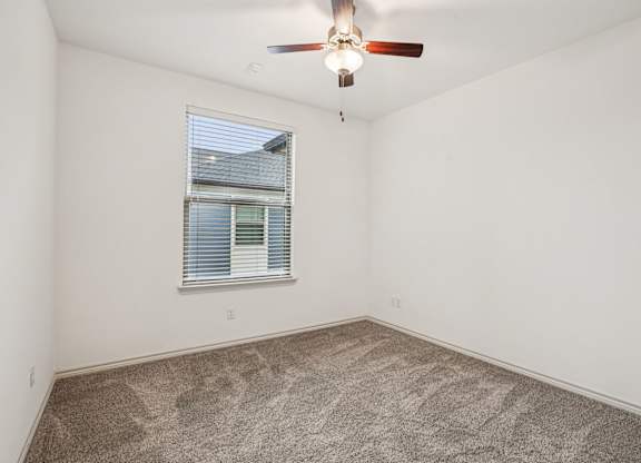 A room with a ceiling fan and a window with blinds.