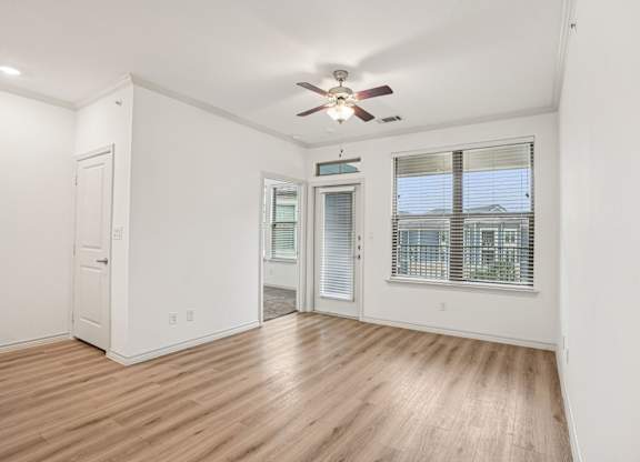 A room with a ceiling fan and wooden flooring.