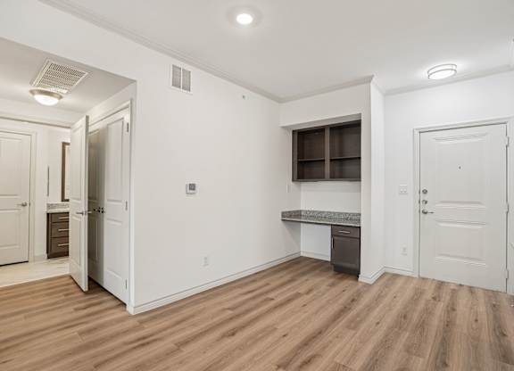 A room with white walls and wooden flooring, with a window and a door visible.