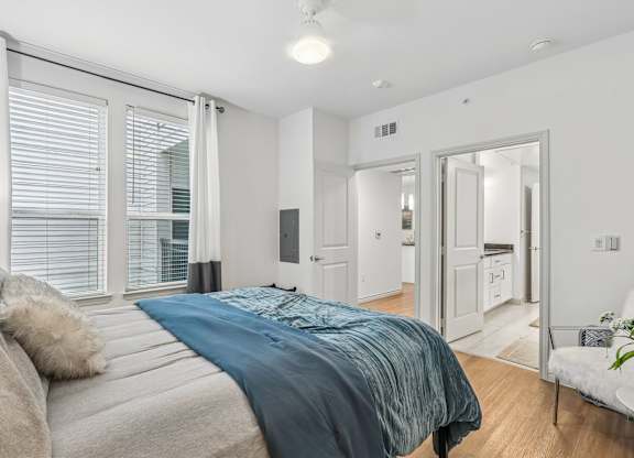 A bedroom with a large bed and a white chair.