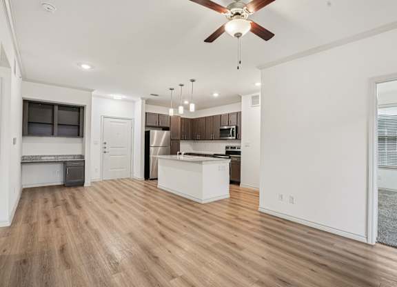 A spacious kitchen and living room with wooden floors and white walls.