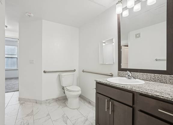 A white toilet in a bathroom with a sink and mirror.