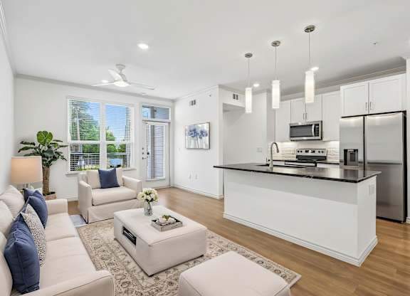 A modern living room with a kitchen area in the background.