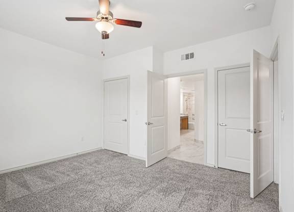 A room with a ceiling fan and carpeted floor.