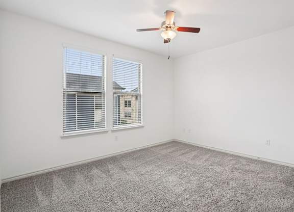 A room with a ceiling fan and carpeted floor.