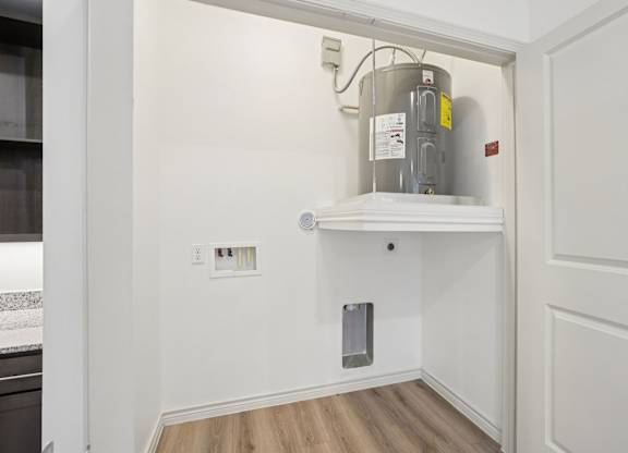 A kitchen with a white cabinet and a stainless steel pot on top.