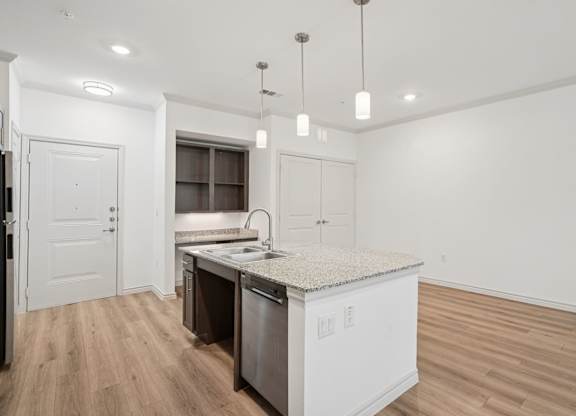 A kitchen with a white counter top and wooden floors.
