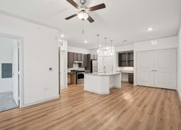 A spacious kitchen with a ceiling fan and wooden flooring.