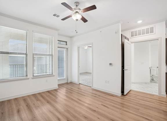 A room with a ceiling fan and wooden flooring.