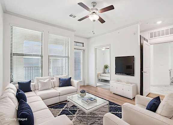 A living room with a white couch, a coffee table, and a television.