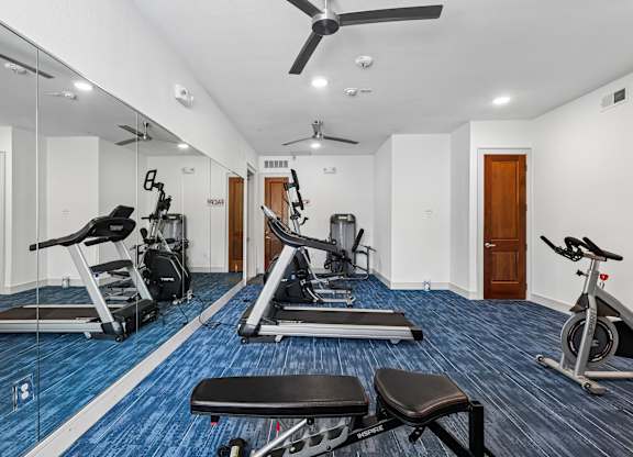 A spacious gym with a variety of equipment including treadmills, exercise bikes, and weight machines.
