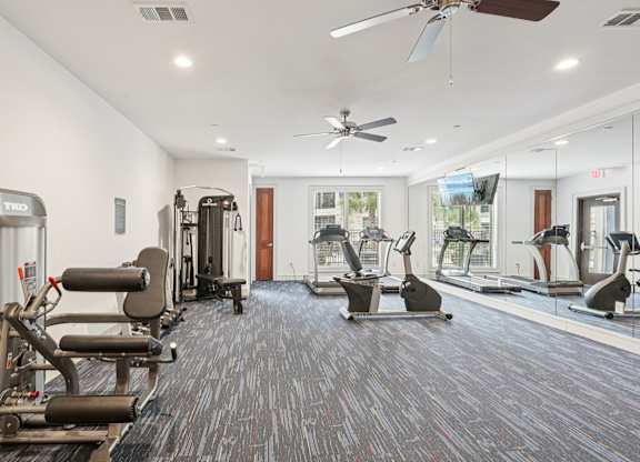 A gym with a variety of equipment including treadmills, stationary bikes, and weight machines.