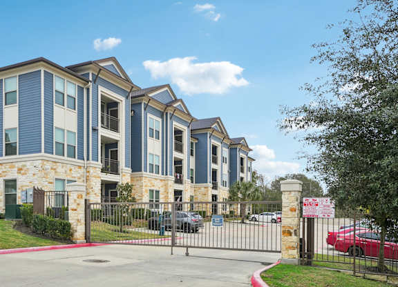 A gated entrance to a residential building with a red car parked in front.