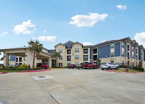 A parking lot in front of a building with cars parked.
