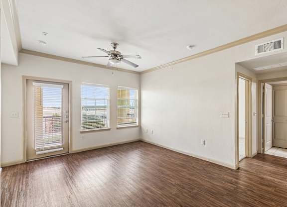 A room with a ceiling fan and wooden floors.