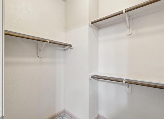 A white closet with two shelves and a door.