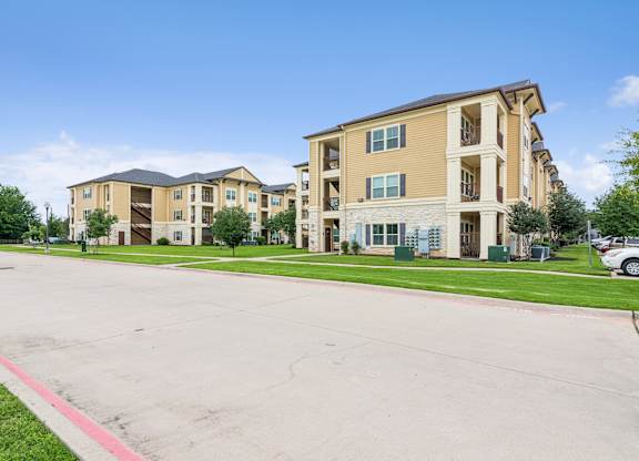 A large apartment complex with a parking lot in front.