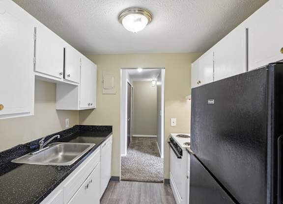 A black fridge in a kitchen with white cabinets.