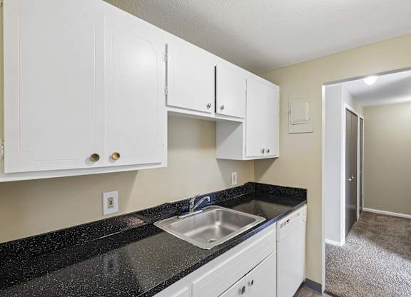 A kitchen with white cabinets and a black countertop.