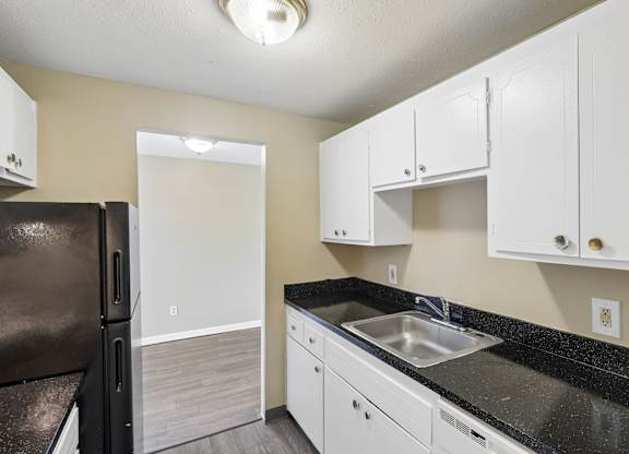 A kitchen with black countertops and white cabinets.
