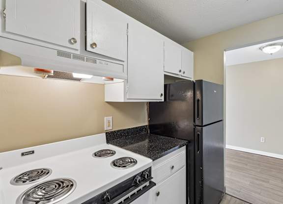 A kitchen with a white stove top and a black refrigerator.