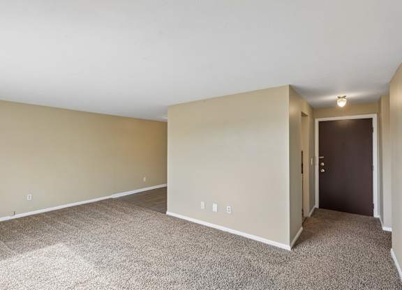 A room with a carpeted floor and a door on the right side.