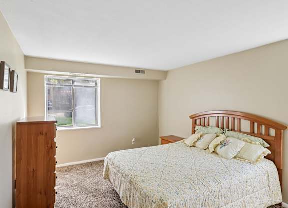 A bedroom with a bed, dresser, and window.