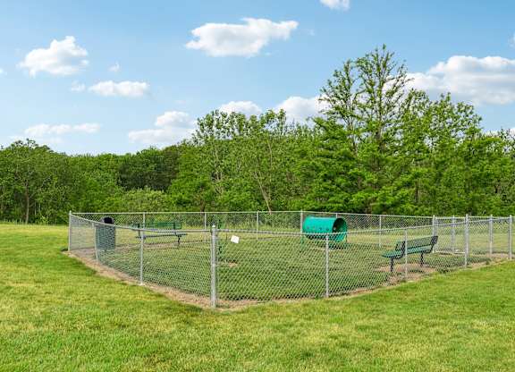 A green fenced area with a bench and a green barrel.