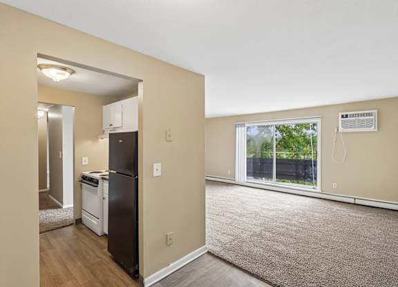 A kitchen with a black fridge and a window with a view of trees.