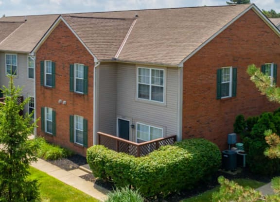 A brick house with green shutters and a well-kept lawn.